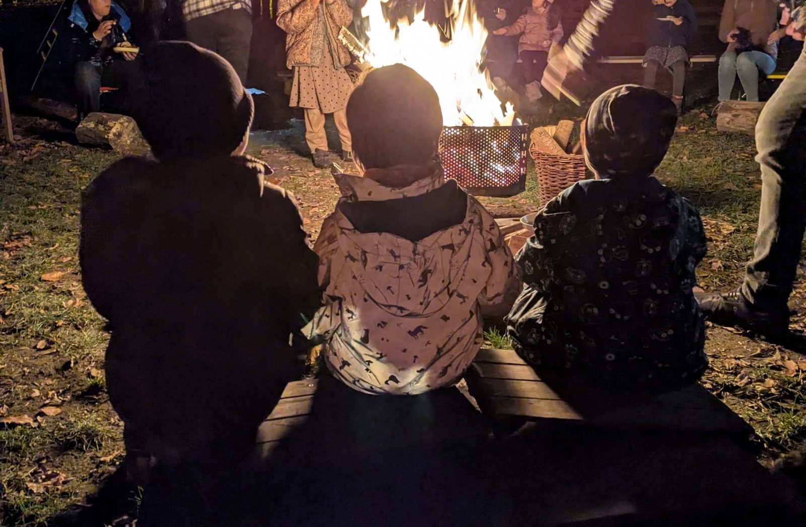 Kinder sitzen am Lagerfeuer beim Laternenfest